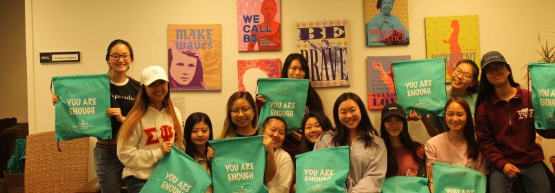 Picture of several women holding up bags that say "You are enough"