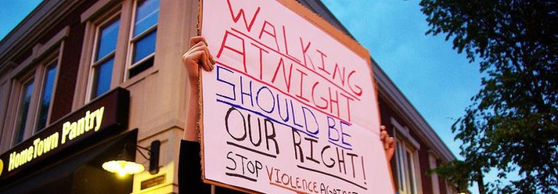Image of a person holding up a sign that says "Walking at night should be our right!"
